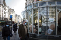 People, wearing face masks to prevent the spread of the coronavirus, walk past a closed restaurant with teddy bears inside, in Paris, Monday, April 19, 2021.(AP Photo/Lewis Joly)