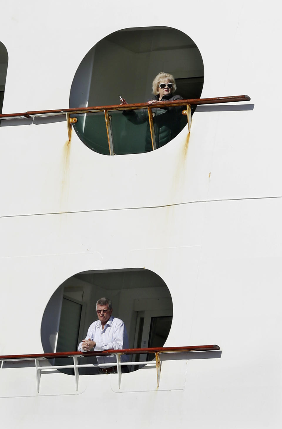 People look out from the Explorer of the Seas cruise ship as it docks at a berth, Wednesday, Jan. 29, 2014, in Bayonne, N.J.. The number of passengers and crew reported stricken ill on the cruise ship has risen to nearly 700. The U.S. Centers for Disease Control and Prevention said Wednesday its latest count puts the number of those sickened aboard the Explorer of the Seas at 630 passengers and 54 crew members. (AP Photo/Mel Evans)