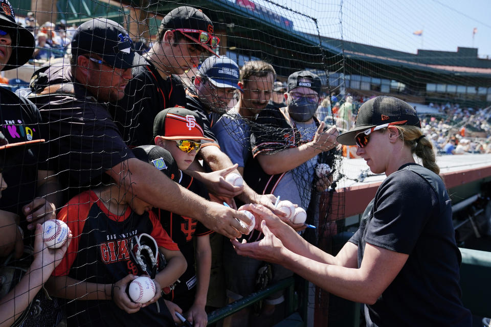 San Francisco Giants assistant coach Alyssa Nakken signs autographs for fans prior to a spring training baseball game against the Colorado Rockies Thursday, March 31, 2022, in Scottsdale, Ariz. (AP Photo/Ross D. Franklin)
