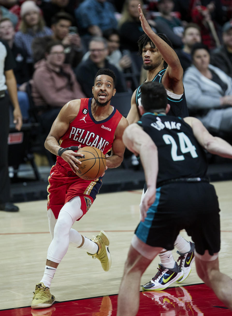 New Orleans Pelicans guard CJ McCollum, left, drives to the basket past Portland Trail Blazers guard Shaedon Sharpe, top right, and forward Drew Eubanks (24) during the second half of an NBA basketball game in Portland, Ore., Monday, March 27, 2023. (AP Photo/Craig Mitchelldyer)