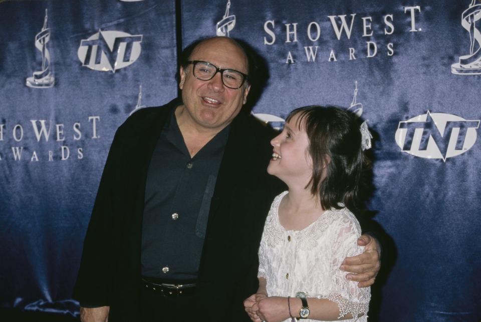 danny devito and mara wilson smiling and hugging at a red carpet event in 1997