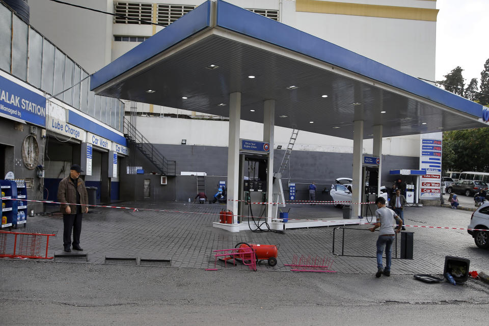 Workers close a gas station during a protest against tight supply of dollars from the central bank in Beirut, Lebanon, Thursday, Nov. 28, 2019. Scores of Lebanese businesses have closed in recent months and thousands of employees were either laid off or are getting half their salaries amid the crisis. Local banks have imposed capital controls worsening the economic conditions amid a liquidity crisis and shortage in U.S. dollars.(AP Photo/Bilal Hussein)