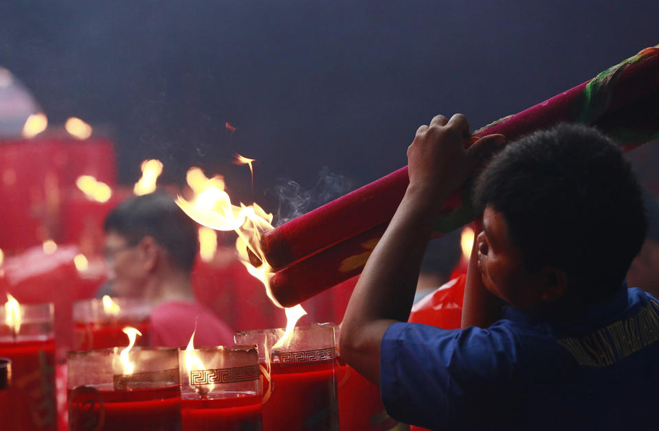 An ethnic Chinese man lights incense sticks during celebrations of the Lunar New Year at the Dharma Bakti Temple in Jakarta, Indonesia, Saturday, Jan. 28, 2017. Ethnic Chinese in the world's most populous Muslim country are celebrating the Year of the Rooster. (AP Photo/Achmad Ibrahim)