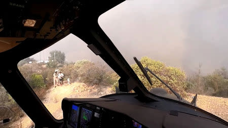 People and their dogs are lead to a helicopter during a rescue made on the fly during the Woolsey Fire in Malibu, California, in this November 9, 2018 still image taken from helmet camera footage by LAFD David Nordquist. LAFD/David Nordquist/Social Media/via REUTERS