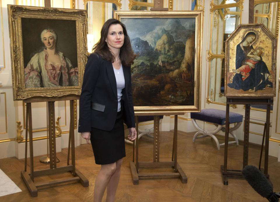 France’s culture minister Aurelie Filipetti, arrives at a ceremony at the Culture Ministry in Paris, Tuesday, March 11, 2014, to return three paintings taken from their owners during World War II, background. The restitution is part of France's ongoing effort to return hundreds of looted artworks that Jewish owners lost during the war that still hang in the Louvre and other museums. (AP Photo/Michel Euler)