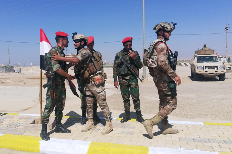 Iraq and Syria border guards soldiers congratulate each other during the opening ceremony of the crossing between the Iraqi town of Qaim and Syria's Boukamal in Anbar province, Iraq, Monday, Sept. 30, 2019. Iraq and Syria have opened a key border crossing between the two neighboring countries seven years after it was closed during Syria's civil war. (AP Photo/Hadi Mizban)
