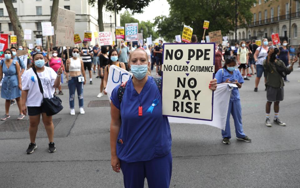 NHS (National Health Service) workers hold placards as they protest outside Downing Street during a march through the streets of London on August 8, 2020, to demand a pay rise. (Photo by ISABEL INFANTES / AFP) (Photo by ISABEL INFANTES/AFP via Getty Images)