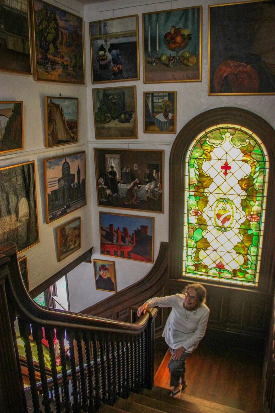 Artist and Greater Fall River Art Association board member Mary Agnes Murphy walks up the main staircase at 80 Belmont St., where a collection of paintings hang created by local artists during the Great Depression as part of the Works Progress Administration.