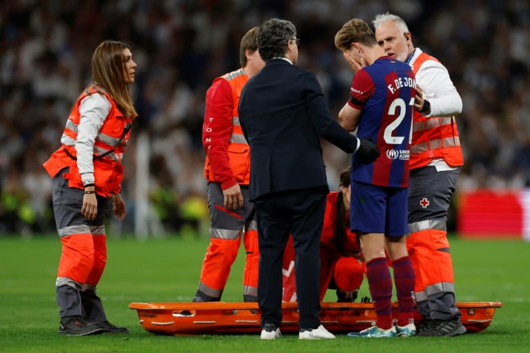 El volante neerlandés del FC Barcelona Frenkie de Jong mientras recibe atención médica durante el partido de Liga ante el Real Madrid, en el Santiago Bernabéu de Madrid, el 21 de abril de 2024 (OSCAR DEL POZO)