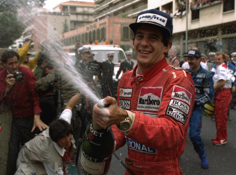 FILE - In this May 12, 1990, file photo, Brazilian driver Ayrton Senna sprays champagne on the photographers to celebrate his career's 30th victory at the Monaco Formula One Grand Prix May 12, 1990. Brazil’s adoration of Ayrton Senna transcends sports. It’s something only someone like Pele can relish in the country of football. When hundreds of thousands of people lined up for hours just to take a final glimpse of Ayrton Senna’s body before his funeral, they were paying tribute to more than a three-time Formula One champion. They were saying farewell to arguably the country’s greatest sporting idol. (AP Photo/Lionel Cironneau,File)