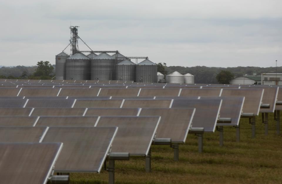 Farm silos appear in the background behind rows of solar panels at the Yellowbud Solar Power Plant on Sept. 28, 2023, in Williamsport, Ohio.