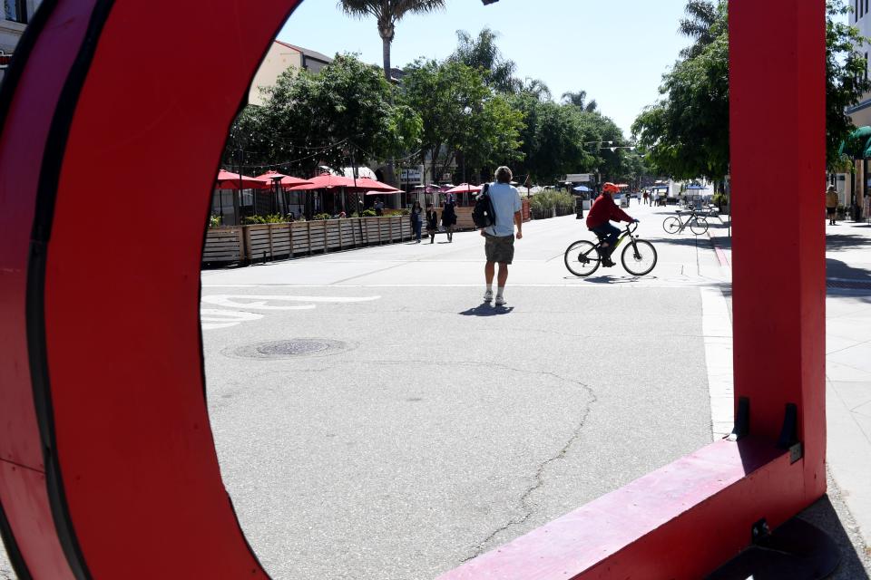 A man on a bicycle passes through Main Street in downtown Ventura on June 21.