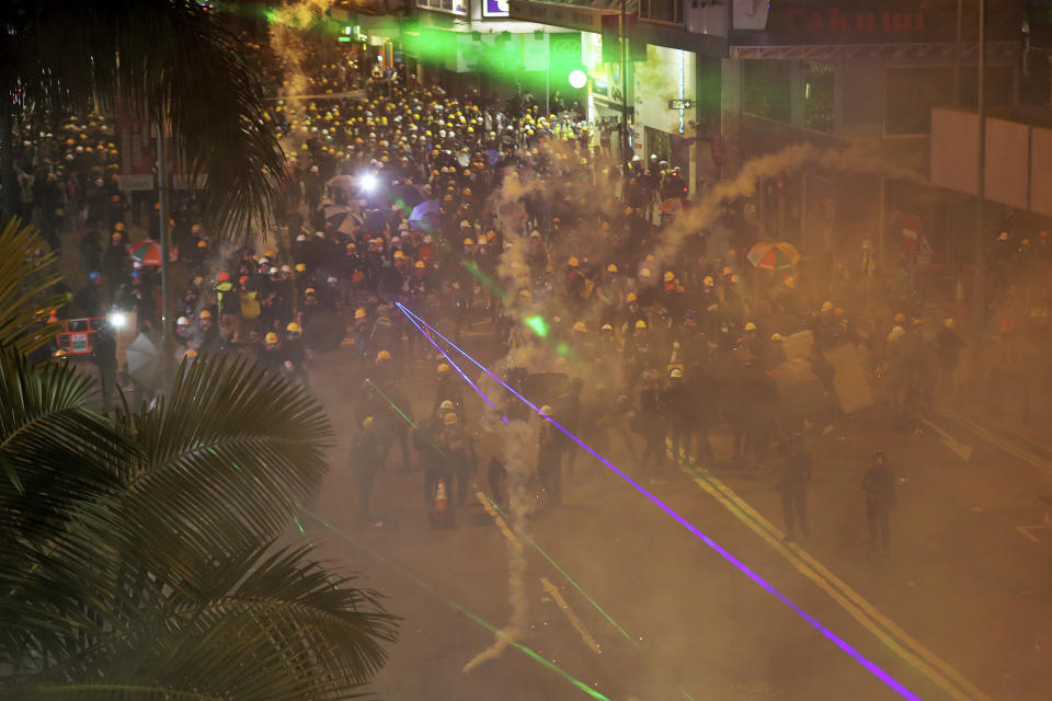 Tear gas smokes raise in front of protesters as they face with riot police during the anti-extradition bill protest at Causeway Bay in Hong Kong, Sunday, Aug. 4, 2019. The first of two planned protests in Hong Kong on Sunday has kicked off from a public park just hours after police said they arrested more than 20 people for unlawful assembly and other offences during the previous night's demonstrations. (AP Photo/Vincent Thian)
