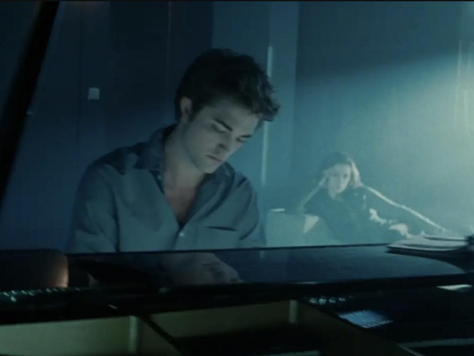 Edward playing the piano while Bella watches in the background in "Twilight"