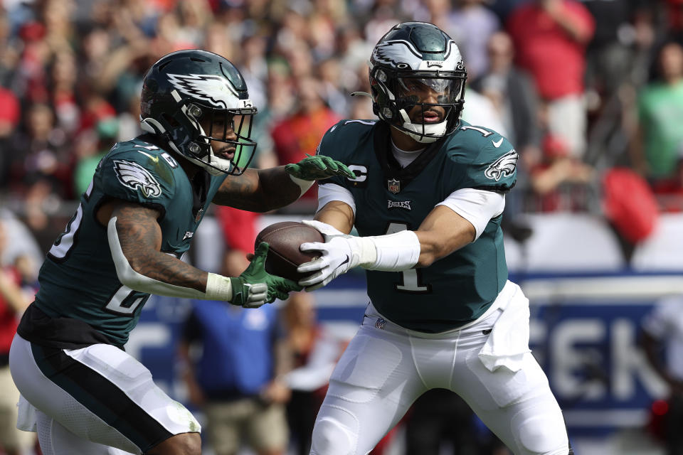 Philadelphia Eagles quarterback Jalen Hurts (1) hands the ball off to running back Miles Sanders (26) during the first half of an NFL wild-card football game against the Tampa Bay Buccaneers Sunday, Jan. 16, 2022, in Tampa, Fla. (AP Photo/Mark LoMoglio)