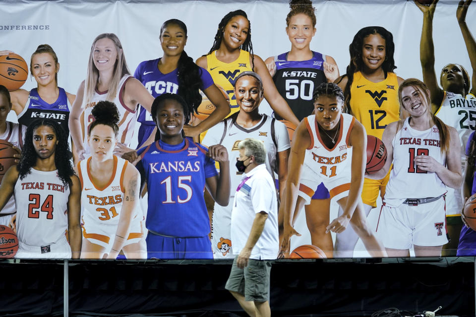 A man passes by a BIG 12 Women's basketball banner during the Big 12 NCAA college basketball media days Tuesday, Oct. 19, 2021, in Kansas City, Mo. (AP Photo/Ed Zurga)