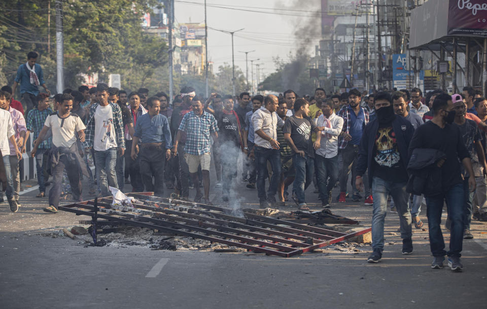 Protestors walk past a damaged road divider during a curfew following a protest against the Citizenship Amendment Bill (CAB) in Gauhati, India, Thursday, Dec. 12, 2019. Police arrested dozens of people and enforced curfew on Thursday in several districts in India’s northeastern Assam state where thousands protested legislation granting citizenship to non-Muslims who migrated from neighboring countries. (AP Photo/Anupam Nath)