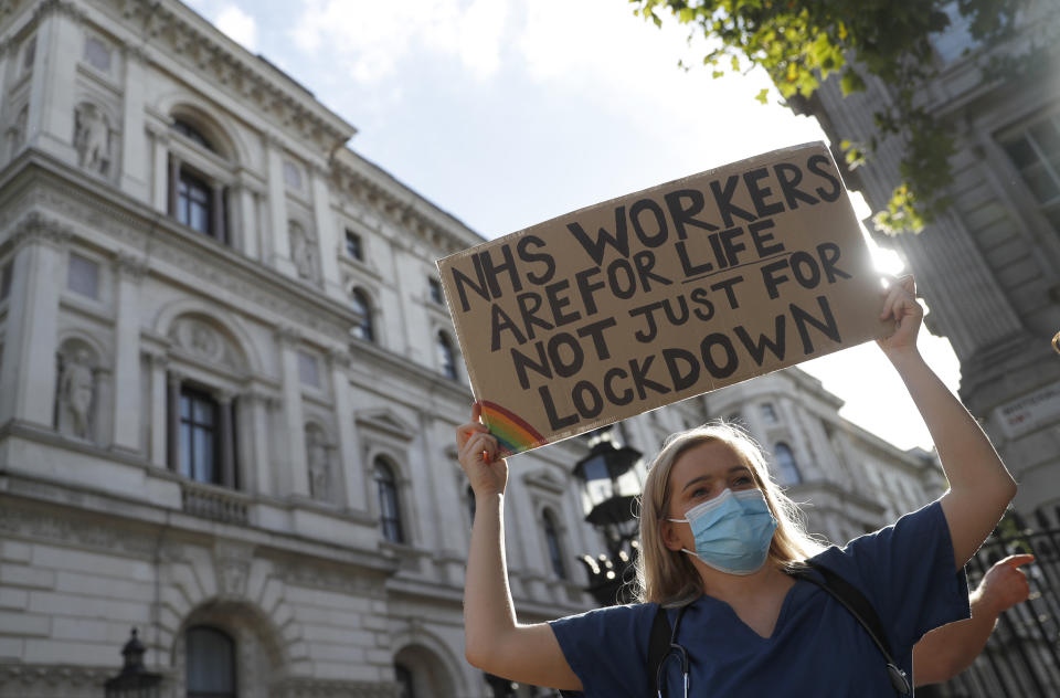 Demonstrators, a number of them nurses and care workers from St Thomas' Hospital, hold placards as they protest for a pay rise in London, Wednesday, July 29, 2020. Heath care unions are launching a campaign for a pay rise for NHS nurses and care workers. (AP Photo/Alastair Grant)