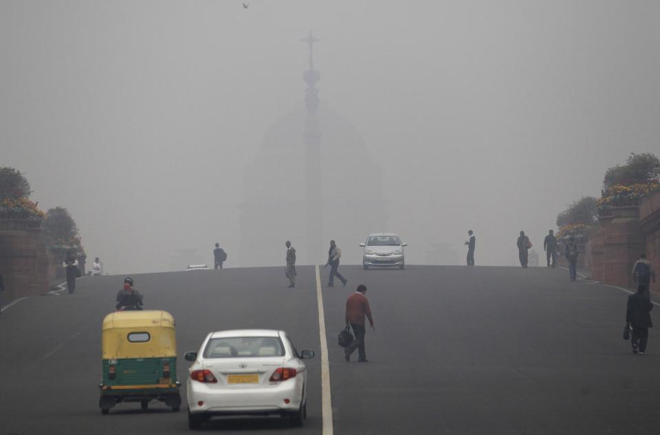 Smog and fog envelop the Indian Presidential Palace, behind, as commuters cross a street in the morning in New Delhi, India, Wednesday, Feb. 5, 2014. On bad days in India’s congested capital, the air is so murky it slows traffic to a crawl because visibility is so poor. Conversations are punctuated with rasping coughs. Weak bands of sunlight filter through a grainy sky. (AP Photo/Tsering Topgyal)