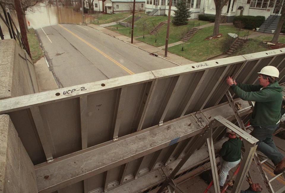 As flood waters crept up Mellwood Avenue, Pat Crawford of MSD connected the panels of a street closure, March 4, 1997
