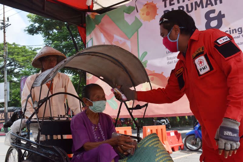 An elderly woman is checked with a thermal scanner by a worker amid the coronavirus disease (COVID-19) outbreak