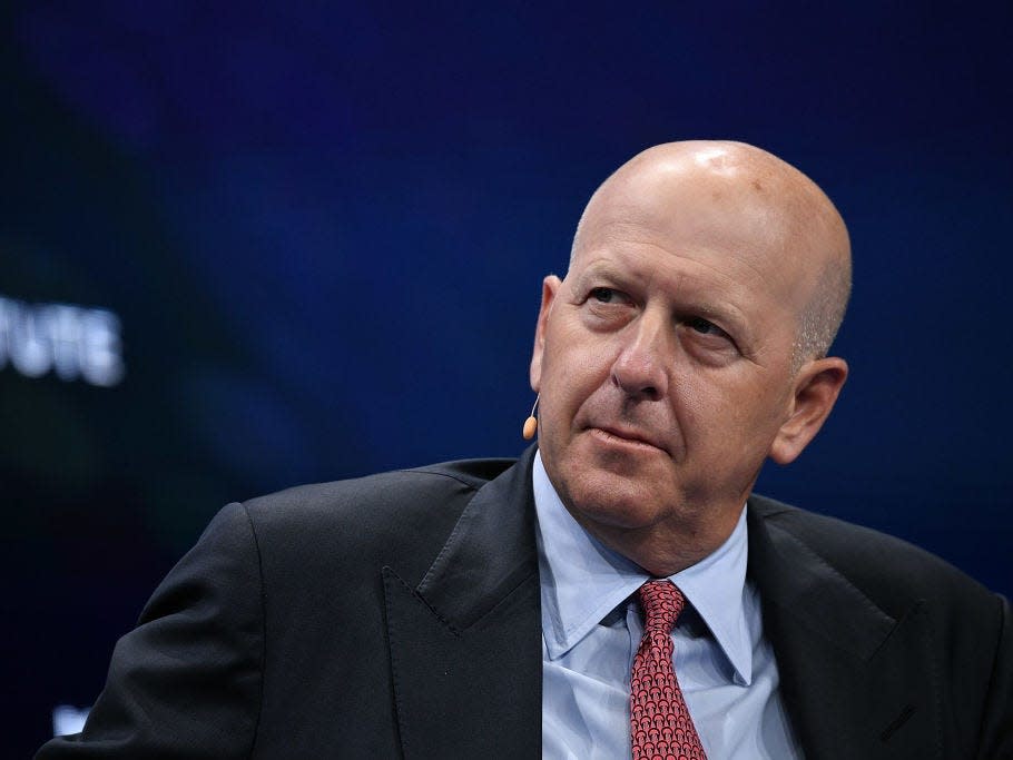 David Solomon, the CEO of Goldman Sachs, wears a dark suit and a red tie while speaking at a conference.