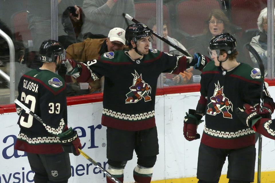 Arizona Coyotes right wing Conor Garland, middle, celebrates his goal against the Pittsburgh Penguins with Coyotes defenseman Alex Goligoski (33) and Coyotes center Christian Dvorak, right, during the first period of an NHL hockey game Sunday, Jan. 12, 2020, in Glendale, Ariz. (AP Photo/Ross D. Franklin)
