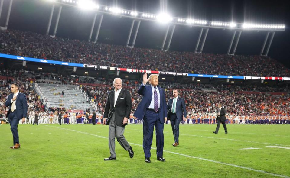 Former President Donald Trump and Governor Henry McMaster walk out onto the field during halftime of South Carolina’s game against Clemson at Williams-Brice Stadium in Columbia on Saturday, November 25, 2023.