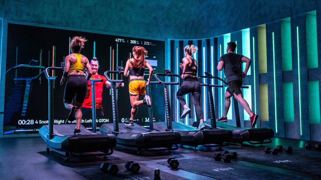  Fiit team running on treadmills in Fiit HQ fitness studio facing a workout screen during treadmill workout 