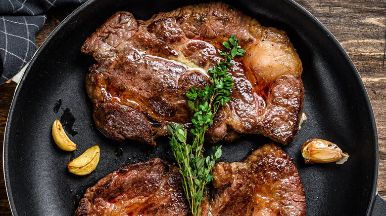 Beef chuck roast in skillet with garlic and microgreens