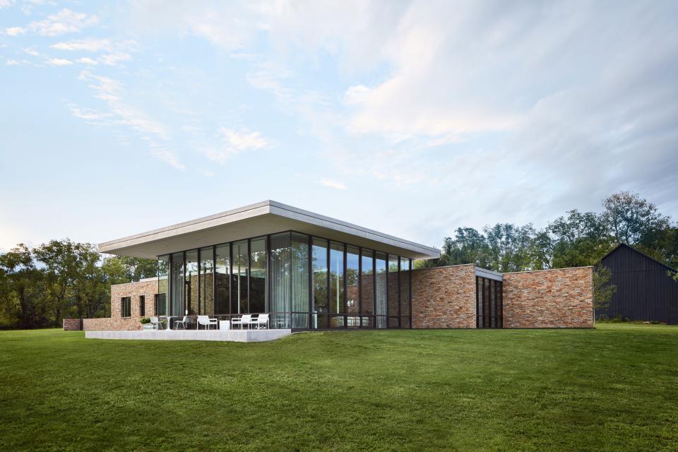 Landscape architect Michael Boucher helped ARO orient the property to overlook the meadow and creek. Beyond the great room, a patio outfitted in Richard Schultz and Bertoia chairs provides two seating areas for taking in the view.