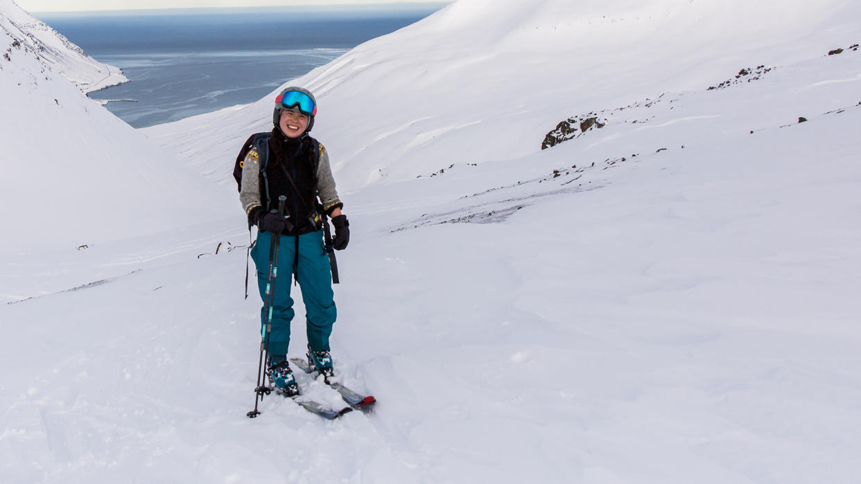  A woman on skis stands on a snowy mountainside, wearing a pair of SunGod Ullrs goggles. 