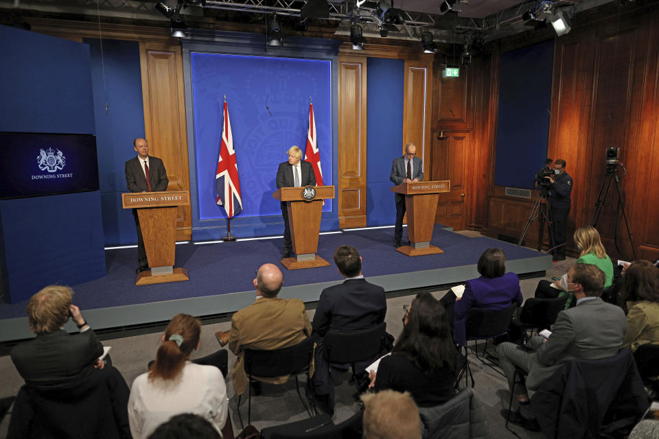 Britain's Prime Minister Boris Johnson, center, Chief Medical Officer for England Chris Whitty, left, and Chief Scientific Adviser Patrick Vallance attend a press conference in London's Downing Street, Wednesday Dec. 8, 2021, after ministers met to consider imposing new restrictions in response to rising cases and the spread of the omicron variant. (Adrian Dennis/Pool via AP)