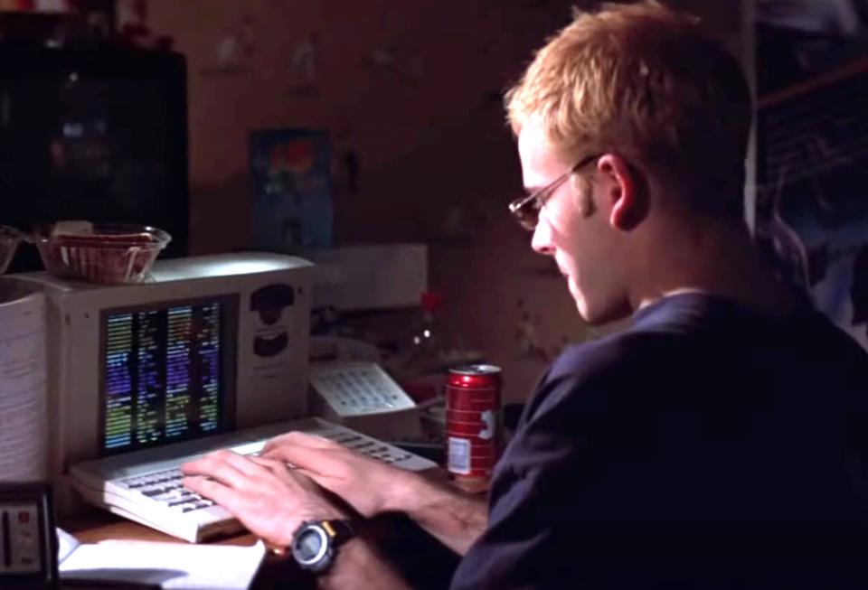 A person typing at a keyboard with a small screen in front of it