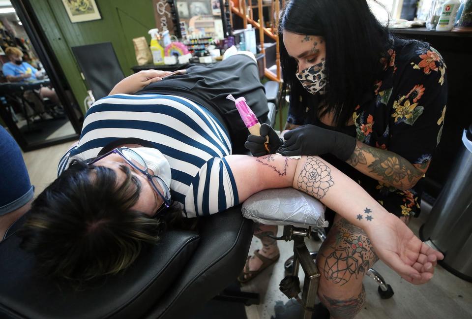 Black Amethyst Tattoo Co. owner Erica Rose tattoos Tressa Watts of Cuyahoga Falls during the shop's flash sale to raise money for local abortion funds on Monday.