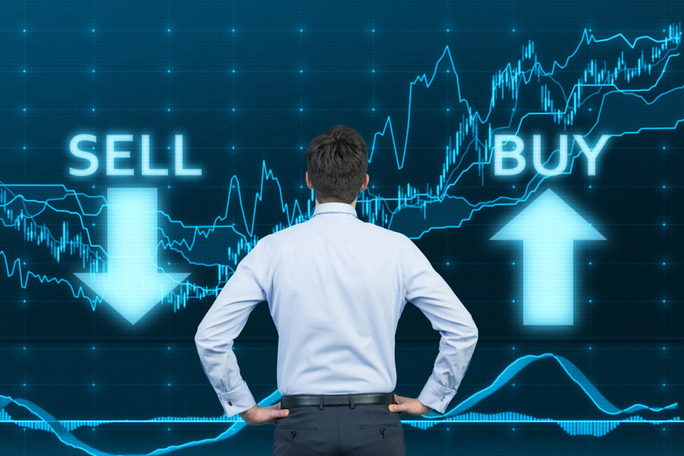 A businessman looking at a stock price chart with the words "buy" and "sell" on it.