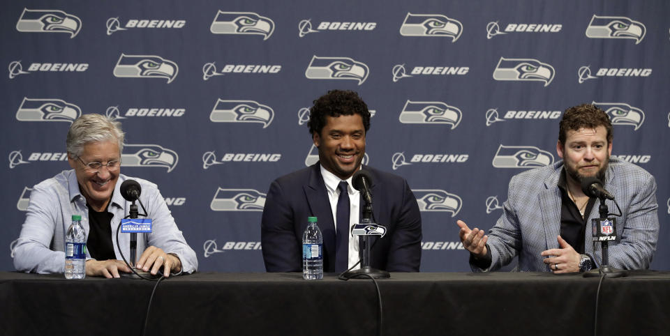 Seattle Seahawks NFL football quarterback Russell Wilson, center, talks to reporters along with head coach Pete Carroll, left, and general manager John Schneider, right, Wednesday, April 17, 2019, in Renton, Wash. Earlier in the week, Wilson signed a $140 million, four-year extension with the team. (AP Photo/Ted S. Warren)