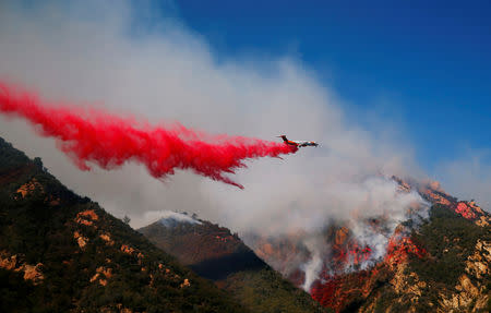 An aircraft drops flame retardant as firefighters battle the Woolsey Fire as it continues to burn in Malibu, California, U.S., November 11, 2018. REUTERS/Eric Thayer