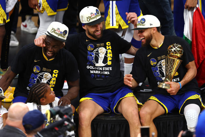 Golden State Warriors players Draymond Green, left, Klay Thompson, center, and Stephen Curry laugh together after winning the 2021-22 NBA championship on June 16, 2022. (Adam Glanzman/Getty Images)