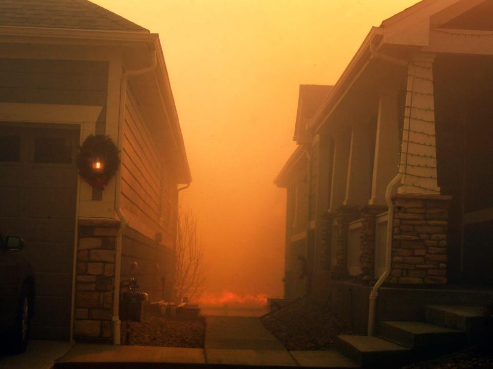 A forest fire rages between two homes in Colorado.