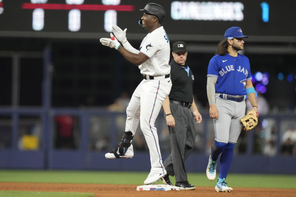 Miami Marlins' Jesus Sanchez, left, reacts after hitting a double during the seventh inning of a baseball game against the Toronto Blue Jays, Monday, June 19, 2023, in Miami. Blue Jays shortstop Bo Bichette, right, looks on. (AP Photo/Lynne Sladky)