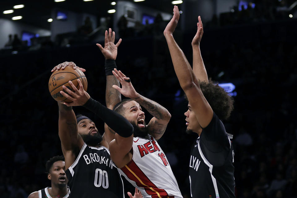 Miami Heat forward Caleb Martin has the ball taken away by Brooklyn Nets forward Royce O'Neale (00) in front of Cameron Johnson during the first half of an NBA basketball game, Saturday, Nov. 25, 2023, in New York. (AP Photo/Adam Hunger)