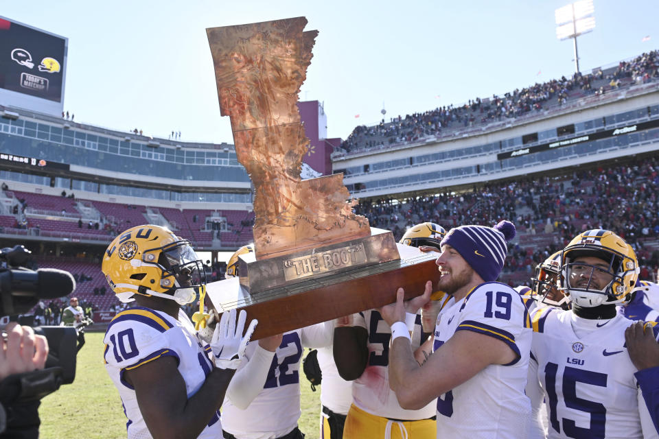 LSU players, left to right, Jaray Jenkins (10), Lane Blue (42), Emery Jones Jr. (50), Jay Bramblett (19) and Sage Ryan (15) carry "the boot" trophy after beating Arkansas 13-10 during an NCAA college football game Saturday, Nov. 12, 2022, in Fayetteville, Ark. (AP Photo/Michael Woods)