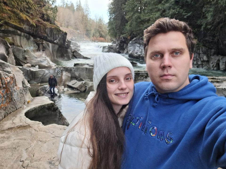 Ludmila and Dmytro Yelenets embracing in front of a stream.