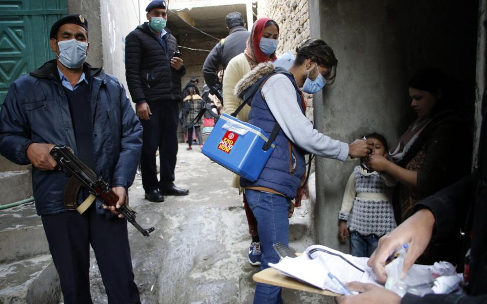 Armed guards in Islamabad, Pakistan accompany polio vaccinators  - Shutterstock