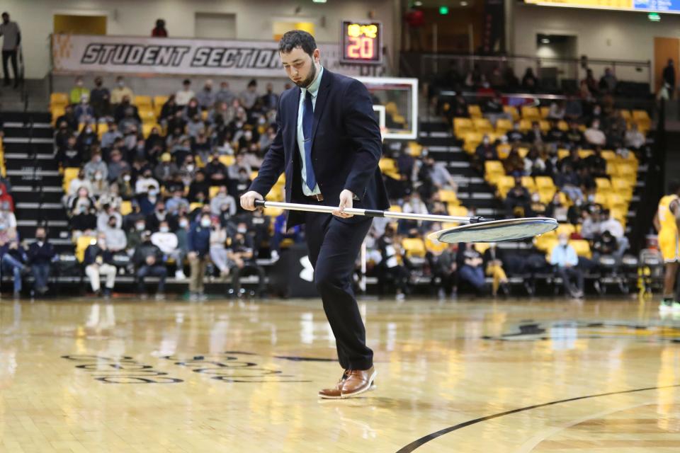 worker examines the court at SECU Arena after several players fell during the course of Delaware's visit to Towson.