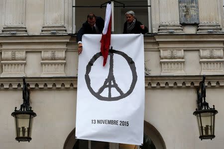 Municipal employees deploy a banner with the drawing "Peace for Paris" by French artist Jean Jullien as people observe a minute of silence at the city hall in Nantes, France, to pay tribute to the victims of the series of deadly attacks on Friday in Paris, November 16, 2015. REUTERS/Stephane Mahe