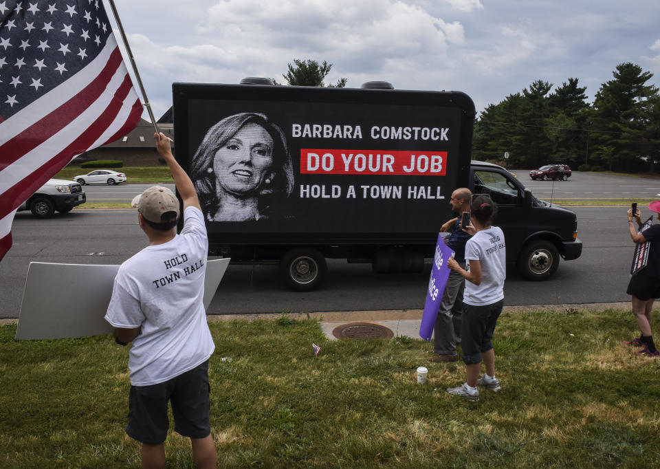 Activists cheer as a new mobile electronic billboard to help unseat Comstock passes by on Leesburg Pike on June 22, 2017 in Sterling, Va. (Photo: Bill O’Leary/The Washington Post via Getty Images)