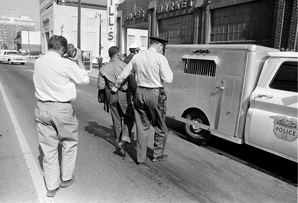 <p>A police officer holds the Rev. Martin Luther King Jr. by his belt as he leads him to the paddy wagon, following arrest at an anti-segregation protest in downtown Birmingham, Ala., on April 13, 1963. An unidentified cameraman is documenting the scene. (AP Photo) </p>