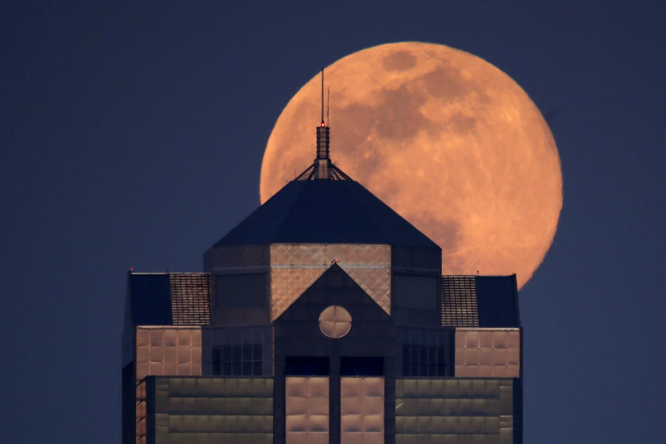 The supermoon rises behind a downtown office building in Kansas City, Mo., Tuesday, April 7, 2020. (AP Photo/Charlie Riedel)